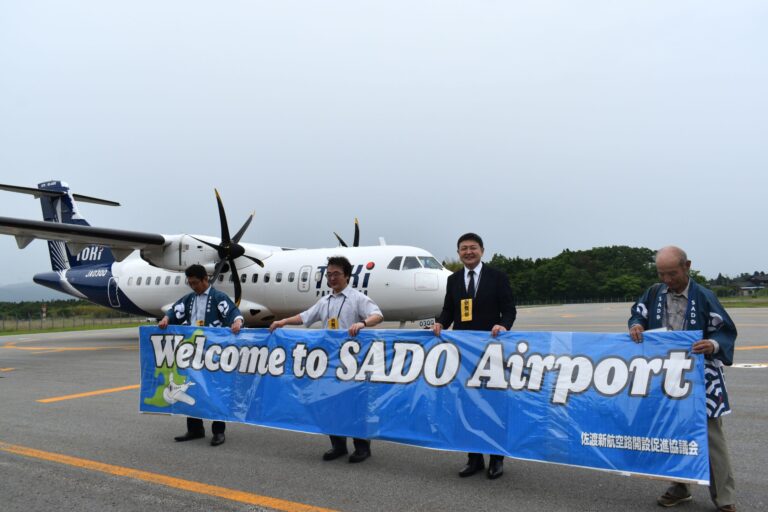 Toki Air aircraft at Sado Airport with "Welcome to SADO Airport" banner, May 28 2026