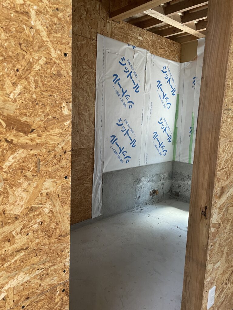 nterior renovation of an old Japanese house, showing new wood framing, a waterproof house wrap, and the original concrete foundation.